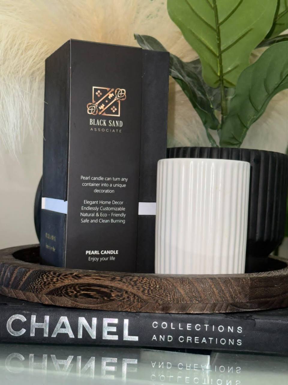 Black Sand pearl candle packaging beside a sculptural white vessel